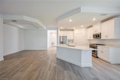 Kitchen with a sink, white cabinetry, light wood f