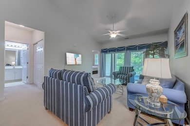 Living area featuring light carpet, ceiling fan, and vaulted ceiling