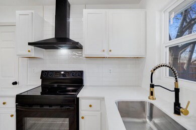 Kitchen featuring wall chimney range hood, black r