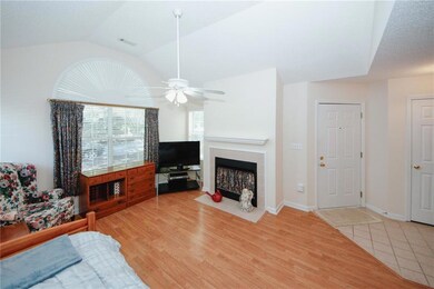 Living area featuring ceiling fan, a tiled fireplace, lofted ceiling, and wood finished floors