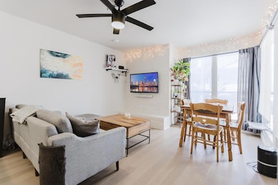 Living area with a ceiling fan and light wood-typ