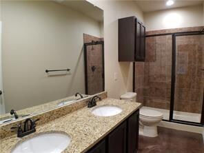 Full bathroom featuring double vanity and a stall shower