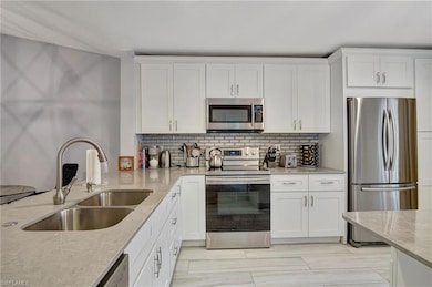 Kitchen with sink, white cabinetry and light quart