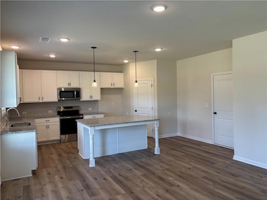 Kitchen featuring appliances with stainless steel finishes, hanging light fixtures, tasteful backsplash, white cabinetry, and recessed lighting