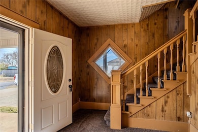Entryway with stairway, wood walls, and carpet