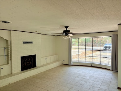 Unfurnished living room featuring a fireplace, a ceiling fan, light tile patterned floors, and crown molding