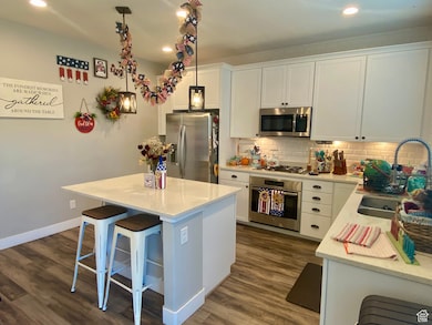 Kitchen with stainless steel appliances, white cabinets, tasteful backsplash, light stone counters, and recessed lighting