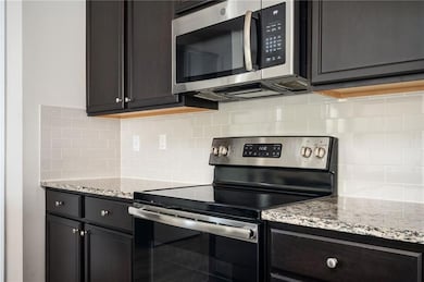 Kitchen with appliances with stainless steel finishes, tasteful backsplash, and light stone counters