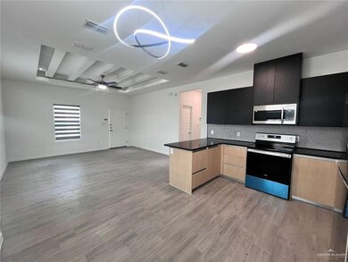 Kitchen featuring dark countertops, light wood finished floors, visible vents, a ceiling fan, and appliances with stainless steel finishes