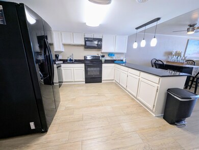 Kitchen with white cabinetry, a peninsula, dark co