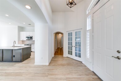 Foyer with a towering ceiling, french doors, light hardwood / wood-style floors, sink, and a chandelier