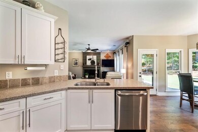 Kitchen featuring dishwasher, white cabinets, a peninsula, a ceiling fan, and real wood-style floors