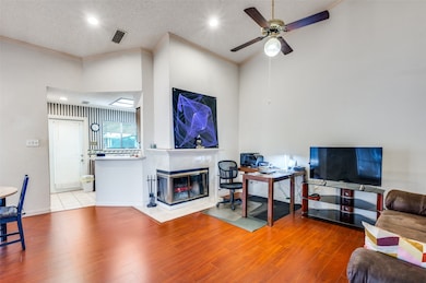 Living area with vaulted ceiling, fireplace LVP wood finished floors, ceiling fan, and crown molding