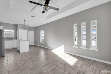 Unfurnished living room with light wood-style flooring, a raised ceiling, visible vents, and baseboards