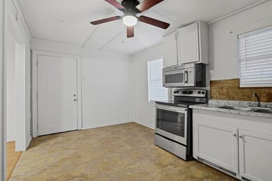 Kitchen with appliances with stainless steel finishes, white cabinetry, tasteful backsplash, and a ceiling fan