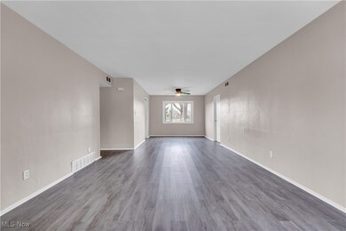 Unfurnished living room featuring a ceiling fan, dark wood finished floors, and baseboards
