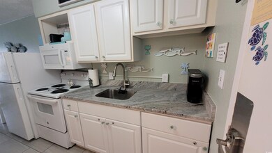 Kitchen with white appliances, white cabinetry, light tile patterned flooring, and light stone counters