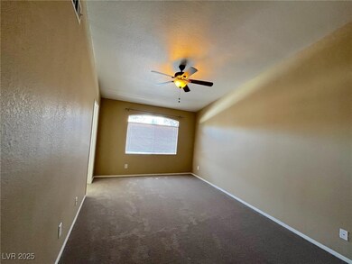 Carpeted empty room with a ceiling fan and baseboa