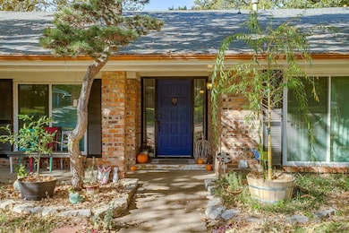 View of exterior entry with a shingled roof, brick siding, and covered porch