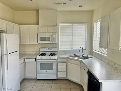 Kitchen featuring white appliances, light countertops, and white cabinets