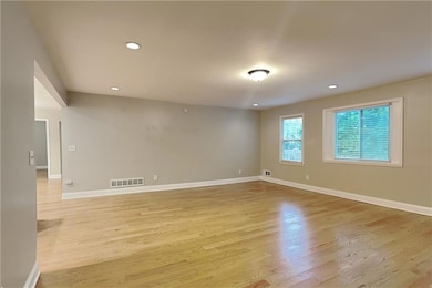 Empty room with light wood-style flooring and recessed lighting