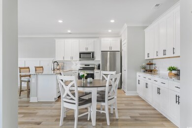 Kitchen featuring light stone countertops, a peninsula, a breakfast bar, white cabinets, and stainless steel appliances