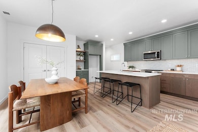 Kitchen with light wood-style floors, a breakfast bar area, light countertops, stainless steel microwave, and a center island with sink