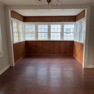 Unfurnished room featuring dark wood-type flooring and wooden walls