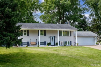 Bi-level home with a chimney, a front yard, concrete driveway, a garage, and a shingled roof
