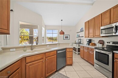 Kitchen featuring appliances with stainless steel finishes, a sink, light tile patterned floors, lofted ceiling, and light countertops