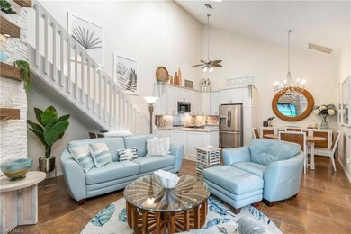 Living area with high vaulted ceiling, stairs, a chandelier, and ceiling fan