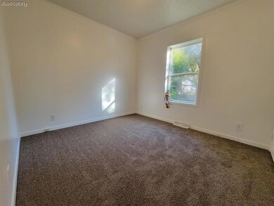 Empty room featuring dark carpet and baseboards