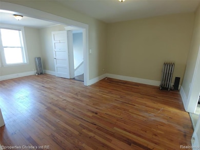 Unfurnished room with light wood-style floors and radiator