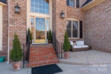 Charming brick front entry with a welcoming staircase, updated lighting, and seasonal-ready greenery.