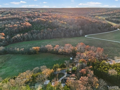 Aerial view of property and surrounding area featuring a forest