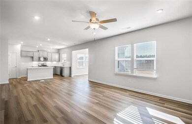 Unfurnished living room with plenty of natural light, baseboards, a ceiling fan, a sink, and recessed lighting