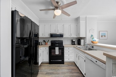 Kitchen featuring black appliances, a sink, a textured ceiling, a ceiling fan, and light countertops