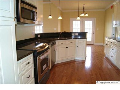 Gourmet kitchen features glazed cabinetry, granite countertops, stainless appliances, and glossy hardwood floors.