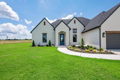French country inspired facade featuring brick siding, a front lawn, a shingled roof, and a garage