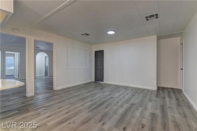 Spare room featuring arched walkways and light wood-type flooring