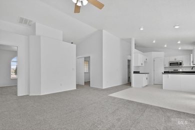 Unfurnished living room featuring light carpet, ceiling fan, and high vaulted ceiling