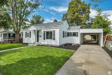 View of front of house featuring a shingled roof, driveway, a chimney, and a carport