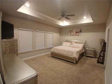 Bedroom with a tray ceiling, ornamental molding, carpet floors, recessed lighting, and ceiling fan