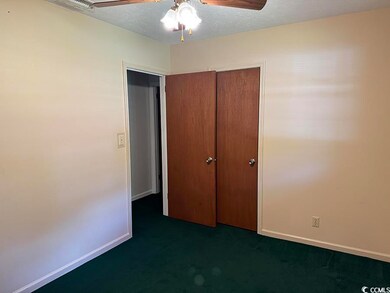 Unfurnished bedroom with dark carpet, a closet, a textured ceiling, and a ceiling fan