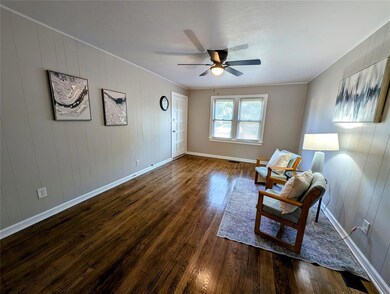 Living area featuring ornamental molding, wood finished floors, baseboards, and a ceiling fan