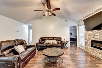 Living room featuring a ceiling fan, lofted ceiling, wood finished floors, and a fireplace