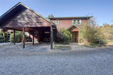 Chalet / cabin with gravel driveway and an attached carport