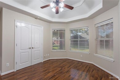 Unfurnished bedroom featuring a raised ceiling, dark wood-style flooring, a closet, and a ceiling fan