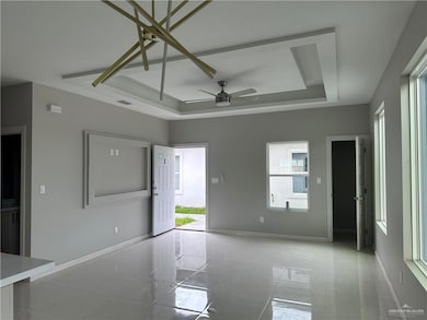 Unfurnished room featuring baseboards, visible vents, a tray ceiling, and ceiling fan