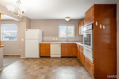 Kitchen with white appliances, light countertops, backsplash, brown cabinets, and a warming drawer